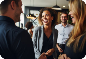 A group of four digital consulting professionals standing in a group laughing with one another. 